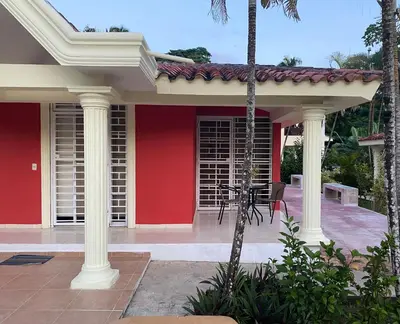 a red house with white columns and a patio at River 1 Basili in Santa Bárbara de Samaná