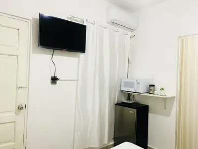 a room with a white curtain and a microwave at Tropical Estudio En El Centro De La Ciudad in San Felipe de Puerto Plata