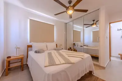 a bedroom with a large white bed with a ceiling fan at la maguana - cozy and beautiful 3BR home with pool in Santiago de los Caballeros