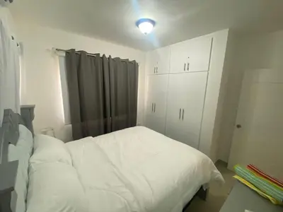 a bedroom with a white bed and a cabinet at Apartamento completo en Bayahibe in Bayahibe