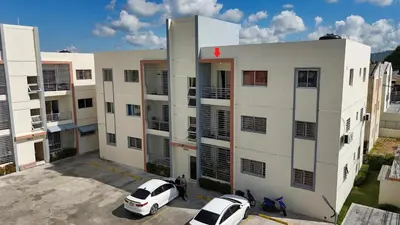 two cars parked in a parking lot in front of a building at Luxury Aparment Bonao in Bonao