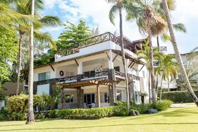 a house with palm trees in front of it at Penthouse frente al mar Playa Las Ballenas in Las Terrenas