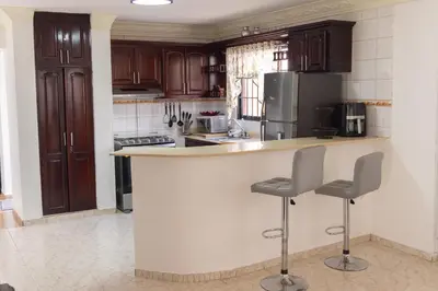 a kitchen with wooden cabinets and a counter with two stools at casa Martinez refugio sereno in Santiago de los Caballeros