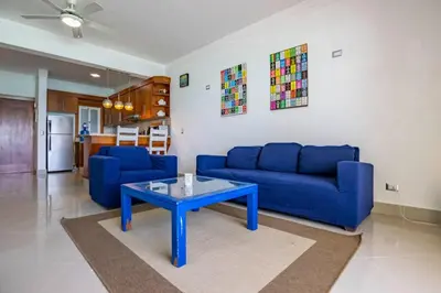 a living room with a blue couch and a table at Beachfront Cabarete Apartment in Cabarete