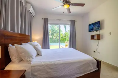 a bedroom with a bed with a ceiling fan and a window at Beachfront Cabarete Apartment in Cabarete