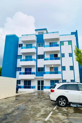 a white car parked in a parking lot in front of a building at Serene Beach Apartment in La Romana