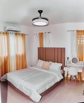 a bedroom with a bed and a table and a chandelier at Serene Beach Apartment in La Romana