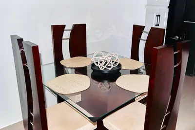 a glass table with three chairs and a bowl on it at Serene Beach Apartment in La Romana