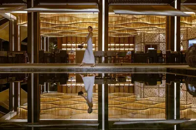 a woman walks through a hotel lobby with a reflection in a pool at Donoma Las Terrenas Beach Hotel & Spa, Autograph Collection in Las Terrenas