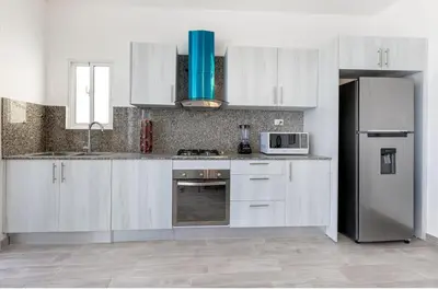 a kitchen with white cabinets and a stainless steel refrigerator at Arena Village Punta Cana El Cortecito in Punta Cana
