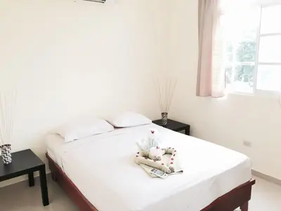 a bedroom with a bed with white sheets and a window at Costambar Seaside Apartment with Pool in San Felipe de Puerto Plata