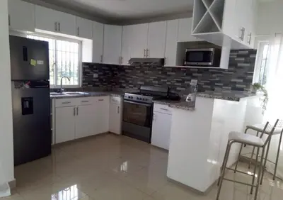 a kitchen with white cabinets and a black refrigerator at The Loft Bayaguana in Bayaguana