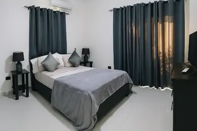 a bedroom with a bed with black curtains and a television at Modern 2BR Apartment 3 Min from Airport with Free Parking in Sosúa