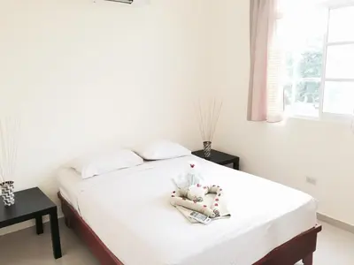a bedroom with a bed with white sheets and a window at Cozy Apartment in Gated Community Costambar, Puerto Plata in San Felipe de Puerto Plata