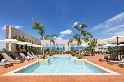 a pool with chairs and umbrellas on a building at Hotel Santiago, Curio Collection By Hilton in Santiago de los Caballeros