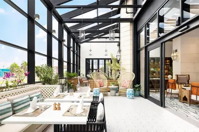 a patio with tables and chairs and windows at Hotel Santiago, Curio Collection By Hilton in Santiago de los Caballeros
