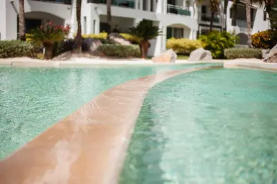 a swimming pool with turquoise water in front of a building at 104 PL - Elegante y moderno, posición perfecta in La Laguna
