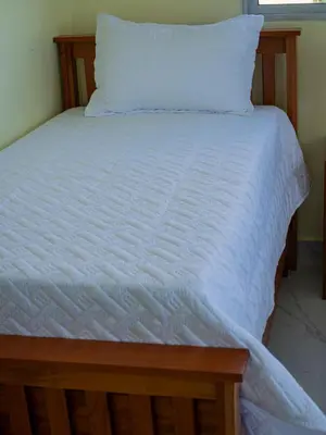 a bed with a white bedspread and a pillow at Villas Vallejuelo in Vallejuelo