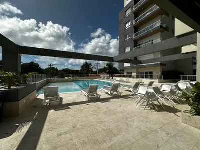 a swimming pool with lounge chairs and a building at Acogedor Apartamento en JUAN DOLIO in Los Corrales