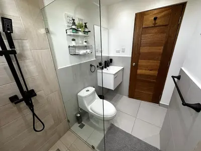 a bathroom with a toilet and a glass door at Acogedor Apartamento en JUAN DOLIO in Los Corrales
