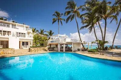 a swimming pool in front of a house and the ocean at KITE BEACH HOTEL Oceanfront Apartments in Cabarete