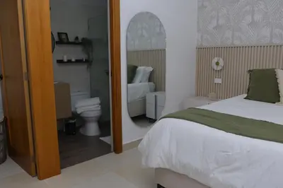 a bedroom with a bed and a bathroom with a toilet at Pool & Gym - 10min Aeropuerto y HOMS - Dream Stay in Santiago de los Caballeros