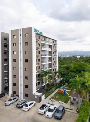a large building with cars parked in a parking lot at Pool & Gym - 10min Aeropuerto y HOMS - Dream Stay in Santiago de los Caballeros