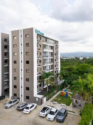 a building with cars parked in a parking lot at Pool & Gym - 10min Aeropuerto y HOMS - Dream Stay in Santiago de los Caballeros