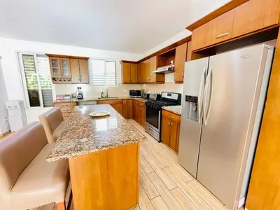 a kitchen with wooden cabinets and a stainless steel refrigerator at Casa feliz in Sosúa