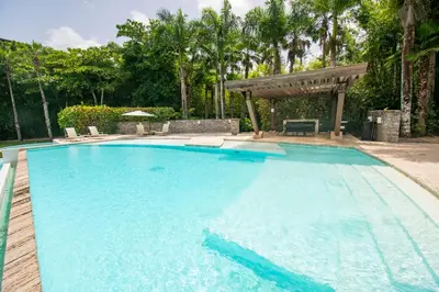 a large blue swimming pool with a pergola at Apto en Casa de Campo en Los Altos 2 in La Romana
