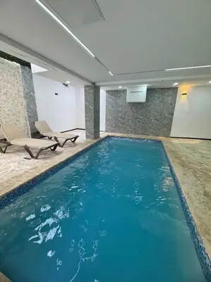 a large swimming pool in a building with two chairs at Apartment in Santo Domingo este in Juan López
