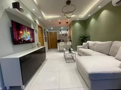 a living room with a couch and a tv on the wall at Apartmento en el corazón de la ciudad con piscina infinita y vista al mar in Santo Domingo
