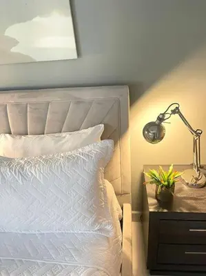 a bed with a lamp and a plant on a night stand at Apartmento en el corazón de la ciudad con piscina infinita y vista al mar in Santo Domingo