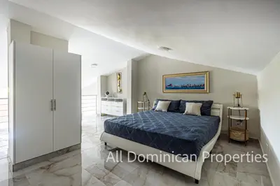 a bedroom with a bed with a blue comforter at Hill Side Condos - Hispaniola in Sosúa