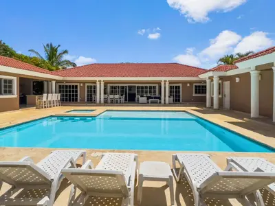 a swimming pool with chairs and a house at Casa Linda Club in Sosúa