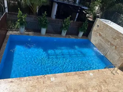 a blue swimming pool with potted plants next to it at New Beachfront at Sunset Apartments 3 Bedroom 2 Bath Gym Pool PS5 in San Felipe de Puerto Plata