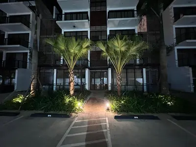 two palm trees in front of a building at night at New Beachfront at Sunset Apartments 3 Bedroom 2 Bath Gym Pool PS5 in San Felipe de Puerto Plata