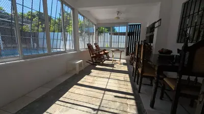 a sunlit room with chairs and a table and windows at Villa Cordero - Las Calderas Bani in Baní