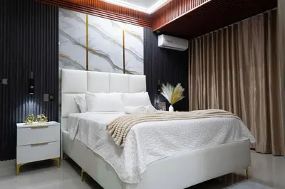 a bedroom with a white bed with a painting on the wall at Acogedor y exclusivo Apt en el gran Santo Domingo in Santo Domingo