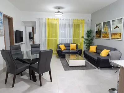 a living room with a black couch and yellow pillows at Boca del Mar III, apartamento 706A in Boca Chica