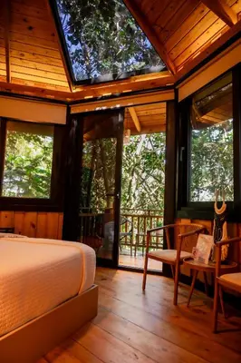 a bedroom with a bed in a room with windows at The Grand Forest Jarabacoa in Jarabacoa