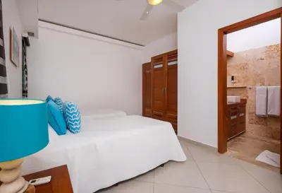 a bedroom with a white bed and a bathroom at Aligio Aparthotel, Beachfront, Las Terrenas in Las Terrenas
