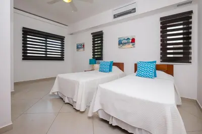 two beds in a room with white walls and windows at Aligio Aparthotel, Beachfront, Las Terrenas in Las Terrenas