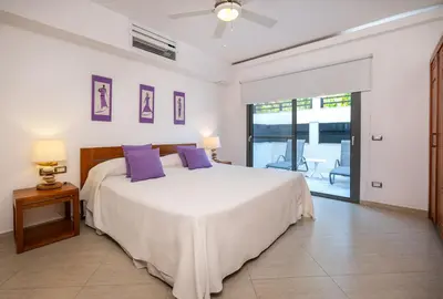 a bedroom with a large white bed with purple pillows at Aligio Aparthotel, Beachfront, Las Terrenas in Las Terrenas