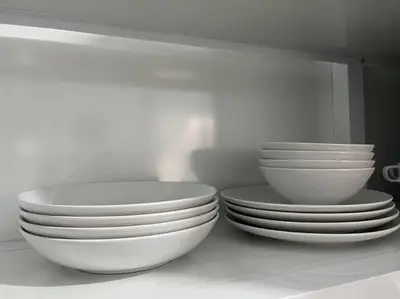 three white bowls and plates sitting on a shelf at Cozy Apartment in the heart of Santiago in Santiago de los Caballeros