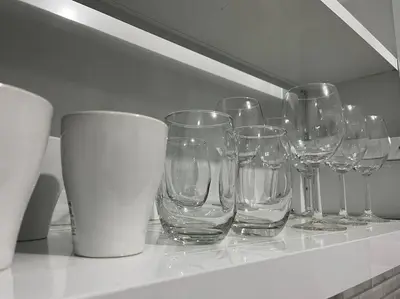 a row of empty wine glasses sitting on a shelf at Cozy Apartment in the heart of Santiago in Santiago de los Caballeros