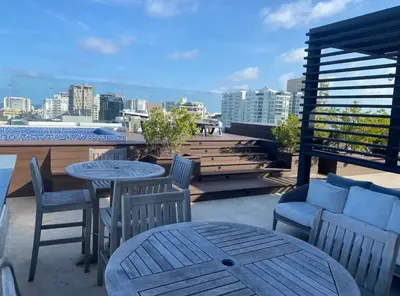 a patio with tables and chairs on a roof at PiantiniTowerCentric SDQ CityView in Santo Domingo