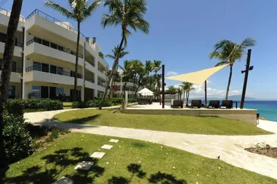 a building with palm trees next to the ocean at Infiniti Blu in Sosúa