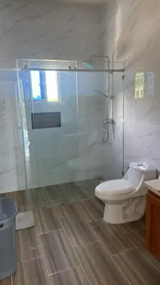 a bathroom with a toilet and a glass shower at Villa familiar in San Felipe de Puerto Plata