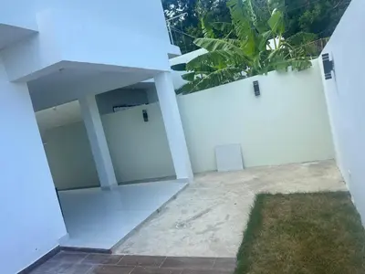 a white building with two garage doors and a plant at Villa familiar in San Felipe de Puerto Plata